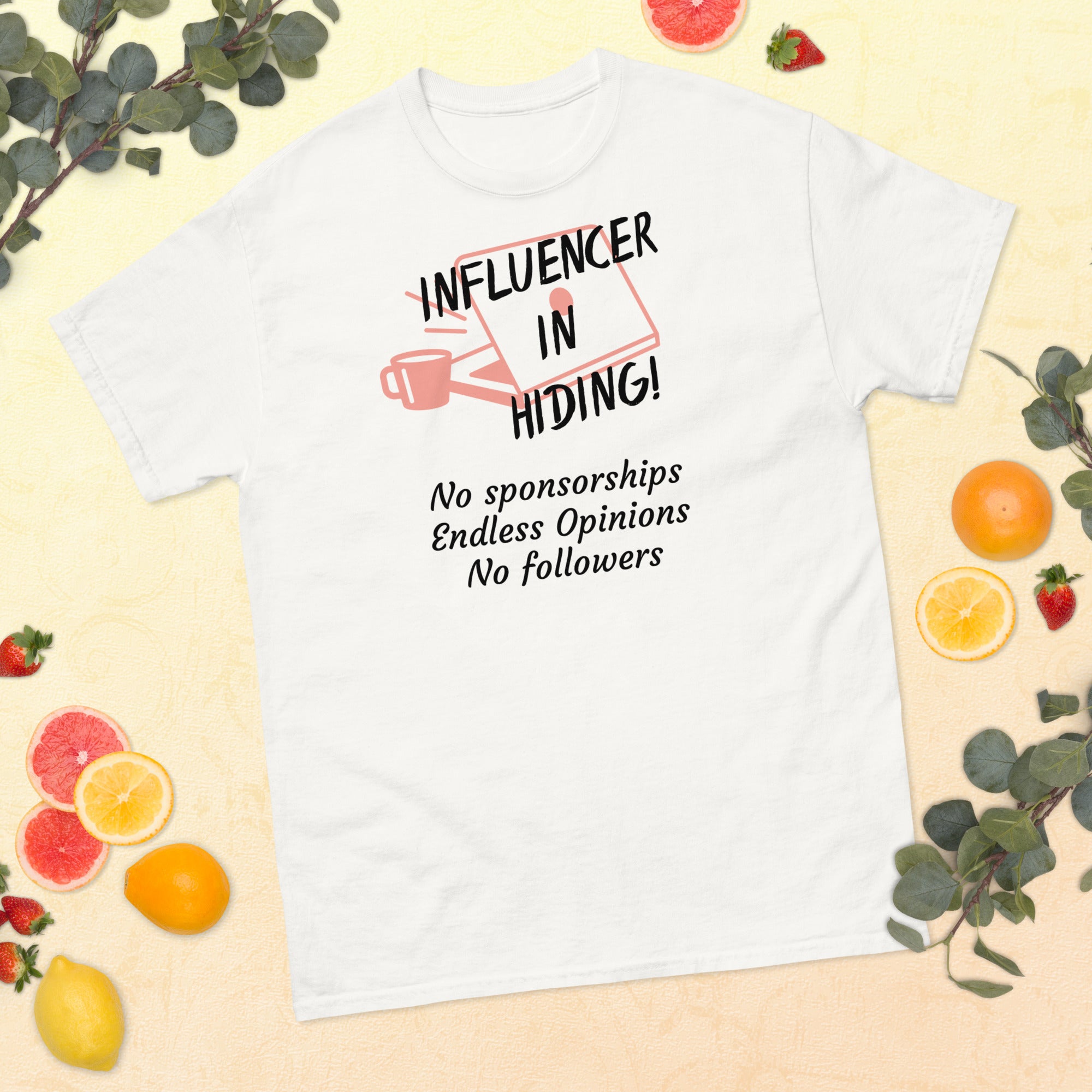 White T-shirt featuring a dark red, hand-drawn graphic of a laptop and coffee mug with bold text reading “INFLUENCER IN HIDING.” The design evokes remote work and digital satire—no sponsorships, no followers, just unapologetic opinions.