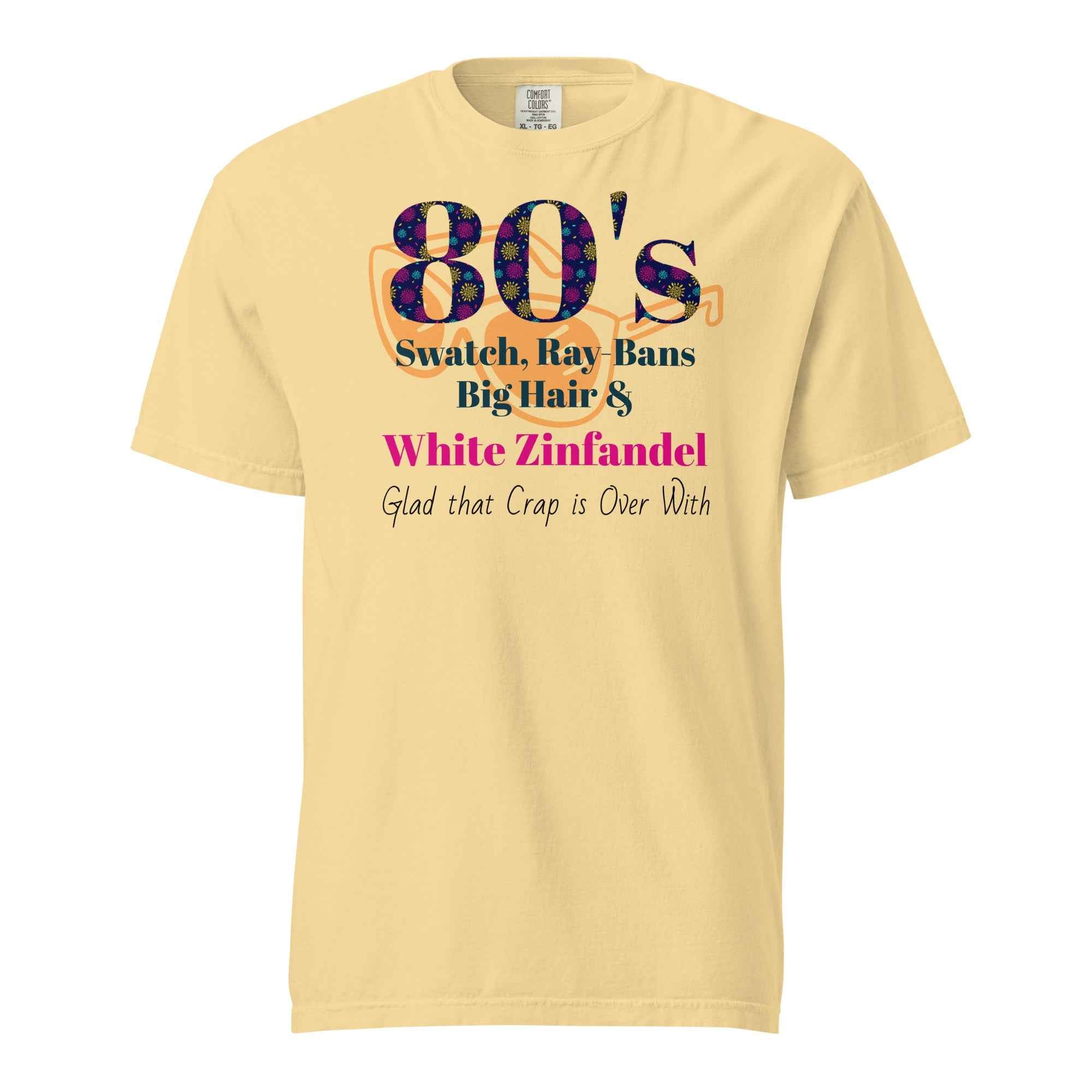 Light yellow T-shirt with colorful text listing 1980s trends—Swatch, Ray-Bans, big hair, and White Zinfandel—followed by the punchline “Glad that crap is over with.” A humorous nod to retro excess.
