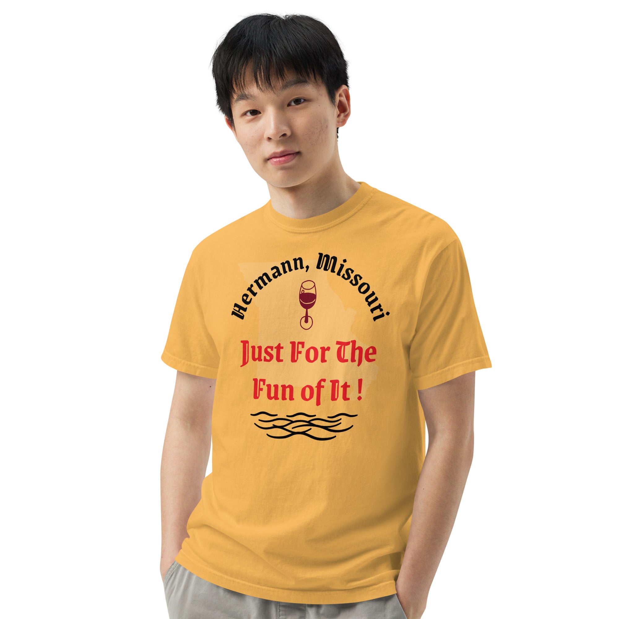 Yellow cotton t-shirt with bold black text reading “Hermann, Missouri – Just for the Fun of It!” styled with wine glasses, river maps, and vintage postcards to evoke spontaneous travel and regional charm.